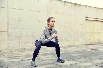 happy woman doing squats and exercising outdoors