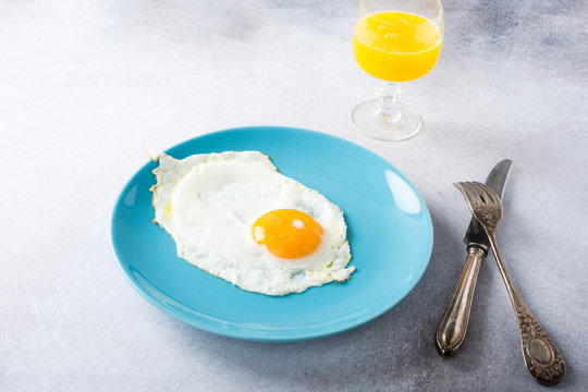 Fried egg on blue plate and orange juice. Healthy breakfast concept with copy space.