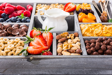 Old gray wooden box with variety of cold quick breakfast cereals and berries for breakfast, healthy eating concept, selective focus.