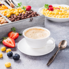 Healthy breakfast with coffee, variety of cold quick cereals and berries in old gray wooden box, selective focus.