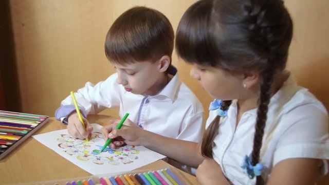 Children draw on paper. Creativity and education concept. The child paints with colored pencils on a white sheet of paper (table)