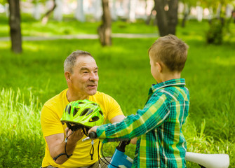 Grandfather gives his grandson a bicycle helmet