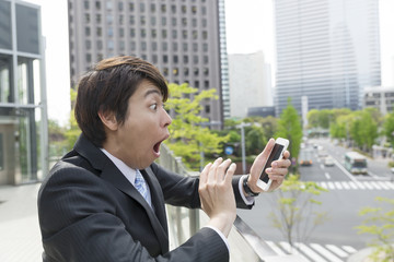 ビジネスマン　スマホ　驚く　ビックリ