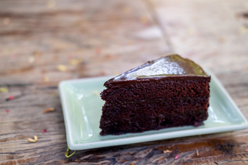 A piece of brownie cake in green ceramic plate on wooden table