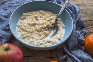 Oatmeal porridge in bowl for breakfast on rustic wooden table