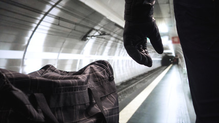 Bomber standing next to his black bomb bag planning a strike. Terrorist in underground subway...