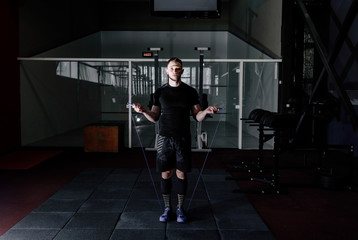 Muscle man skipping rope. Athlete using jump ropes for the workout in a cross-training gym. Man jumping rope at the gym