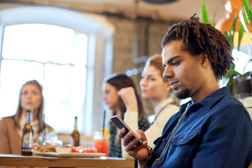 man with smartphone and friends at restaurant