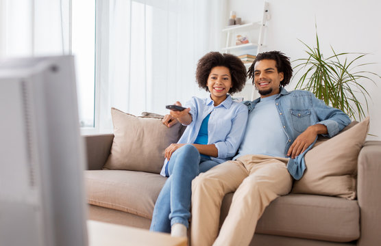 Smiling Couple With Remote Watching Tv At Home