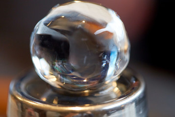 hand-cut ice ball on top of cocktail shaker at bar
