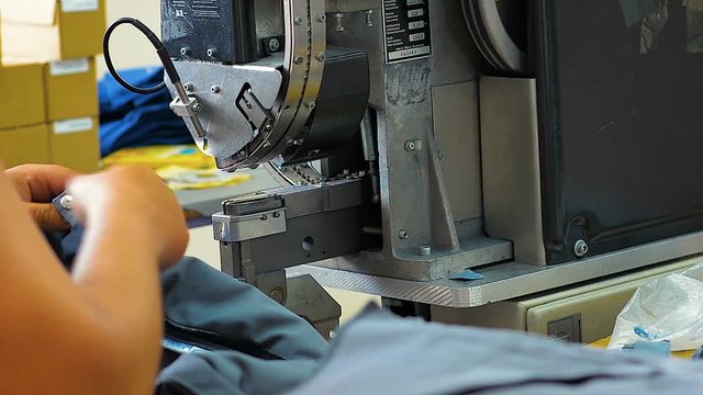 Worker at garment factory uses lazar equipment for textile production  