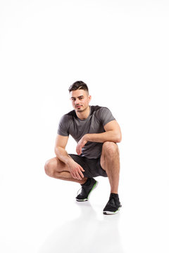 Young handsome fitness man in gray t-shirt, studio shot.