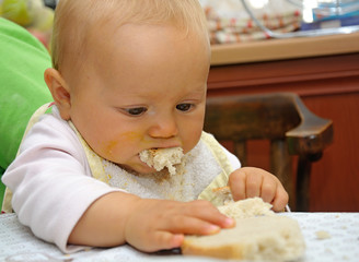 Small baby eating bread