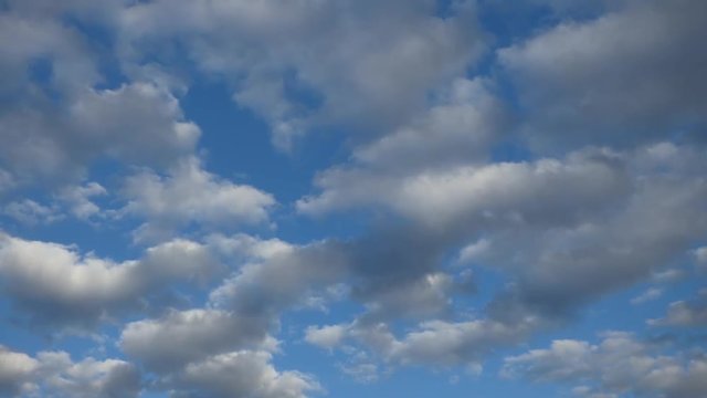 Cloudy blue sky, lot of white and gray clouds slowly fly away. Spring day or early evening, cold weather. Natural background - cloudscape. Time lapse (double)
