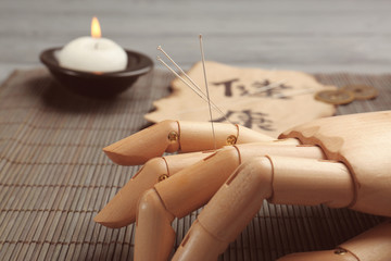 Model of hand with acupuncture needles on bamboo mat