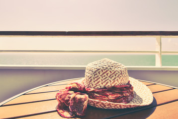 Summer hat on wooden table of cruise ship balcony.