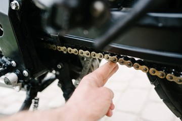 Man checks the chain tension in motorcycle