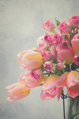 fresh pink and yellow tulips and roses close up on gray background, retro toned