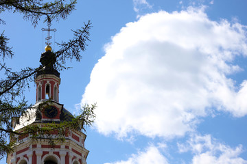 Christian church and branches of a coniferous tree against blue sky