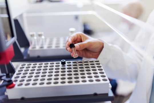 Scientist putting samples in research equipment. Scientist carrying out experiment in research laboratory.