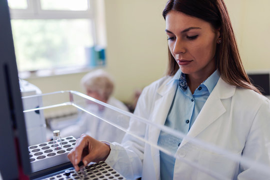 Scientist putting samples in research equipment. Scientist carrying out experiment in research laboratory.