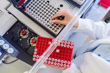 Scientist putting samples in research equipment. Scientist carrying out experiment in research laboratory.