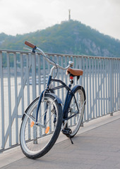 Retro style design bicycle parked next to river at urban environment