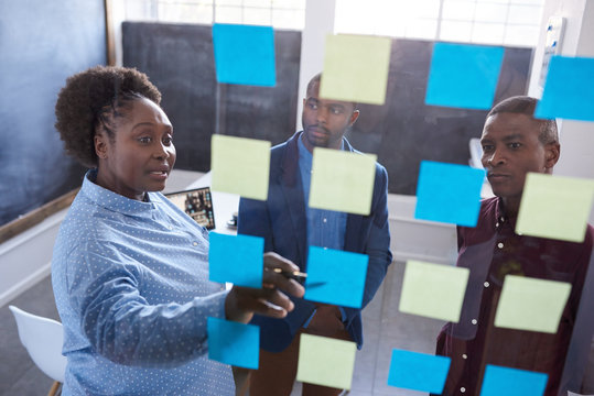 African coworkers strategizing with sticky notes on a glass wall