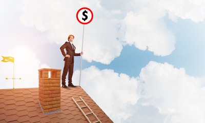 Businessman on house roof showing roadsign with money concept and looking at city. Mixed media