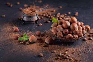 Hazelnut, coffee beans and cocoa powder in dark background.