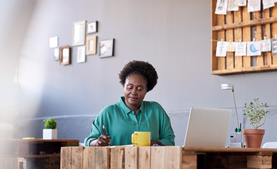 African businesswoman writing in a book at her office desk