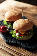 Two handmade burgers with beef, salad and cheese on wooden table.
