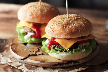 Two handmade burgers with beef, salad and cheese on wooden table.
