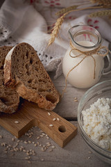 Fresh dairy products. Milk, cottage cheese, sour cream, multigrain homemade bread and wheat on rustic wooden background.