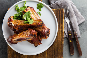 Pork ribs on white plate on slate background
