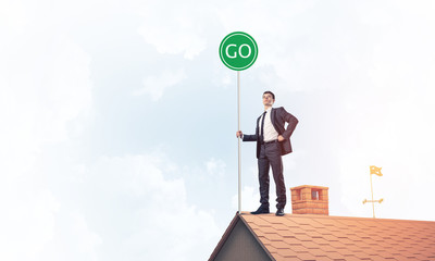 Businessman in suit on house top with ecology concept signboard.