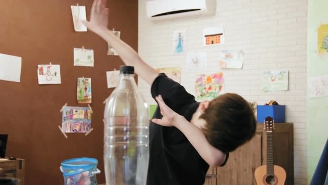 Cute little boy playing water bottle flip challenge in his room