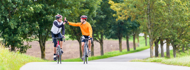 Racing cyclists after sport and giving high five