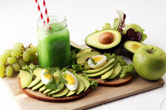 Sandwich with avocado and poached egg - green smoothie - healthy breakfast concept