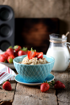 Oatmeal with fresh strawberries and milk on an old wooden background. Healthy breakfast. Healthy food.