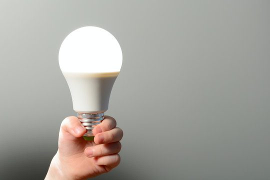 Children's hand holds a glowing led bulb