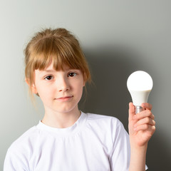 Cute little girl holding a luminous led light bulb