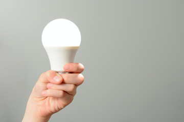 Children's hand holds a glowing led bulb