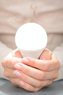 Female hands holding a glowing led bulb