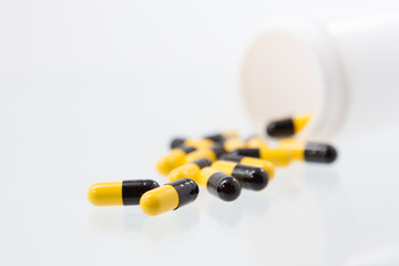 Yellow and black pills and pill bottle, selective focus.