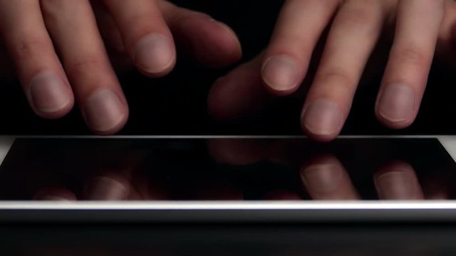 Man types text message on electronic tablet. Hands close-up.