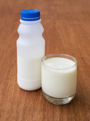 the glass and bottle of milk on old wooden table
