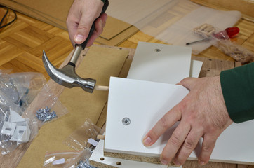 Inserting wooden dowels in to a particle board with hammer