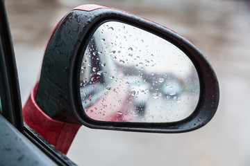 raindrops on side rearview mirror in rainy day