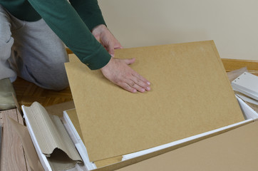 Man taking out of a box elements of a new piece of furniture